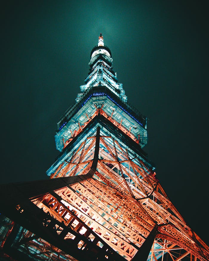 services-02 Stunning low-angle capture of Tokyo Tower glowing under night sky, showcasing its architectural brilliance.