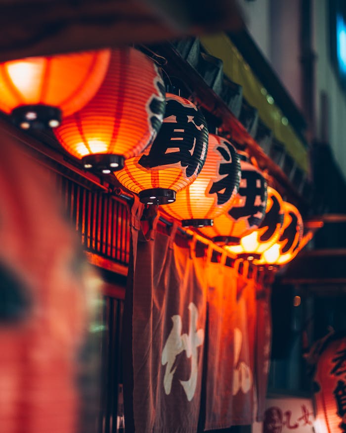 our-story Illuminated Japanese lanterns casting a warm glow outside a restaurant in Tokyo, Japan.